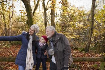 Multi Generation Family Enjoying Walk In Fall Landscape