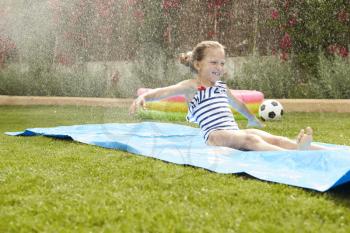 Girl Having Fun On Water Slide In Garden