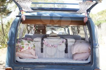 Open back of a retro camper van, with luggage and cushions