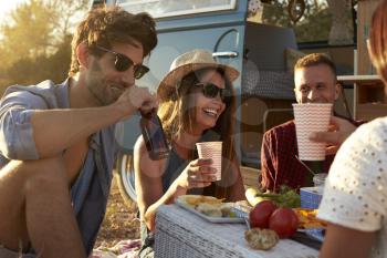 Friends on a road trip having a picnic beside a camper van