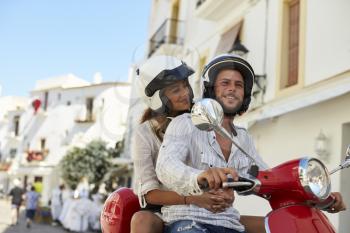 Young adult couple on a motor scooter in a street, Ibiza