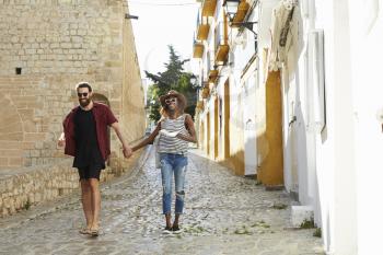 Couple on holiday walking in Ibiza streets with a guidebook