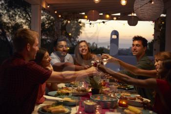 Friends make a toast at a dinner party on a patio, close up