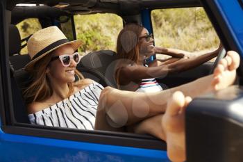Two Female Friends Driving Open Top Car On Country Road