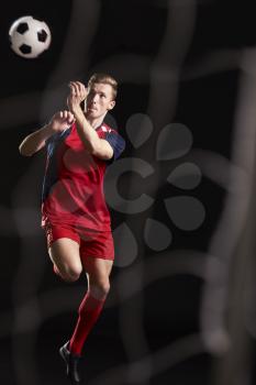 Professional Soccer Player Jumping To Head Ball In Studio
