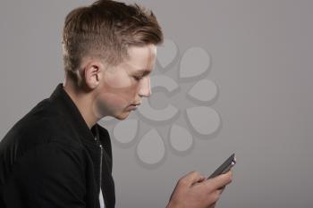 White teenage boy using mobile phone, waist up, side view