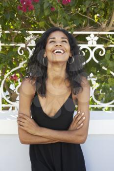 Laughing Latin American woman outdoors with arms crossed