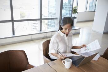 Businesswoman Working Alone On Laptop In Office Boardroom