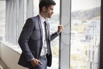 Young Businessman Looking Out Of Window In Office
