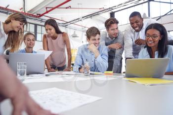 Young business team gathered around two laptops in an office