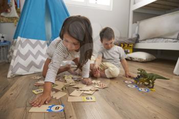 Two Children Playing Number Puzzle Game Together In Playroom