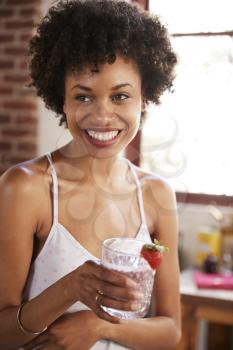 Happy mixed race woman holding smoothie, vertical