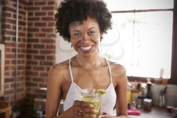 Happy mixed race woman holding smoothie, looking to camera
