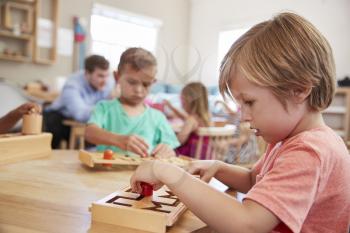 Female Pupil Working At Table In Montessori School