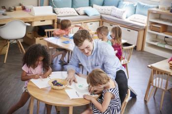 Teacher And Pupils Practicing Writing In Montessori School
