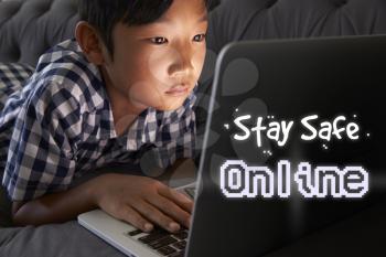 Boy At Home Using Laptop With Stay Safe Online Message
