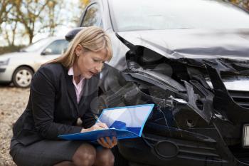 Female Loss Adjuster Writing Report On Damaged Car