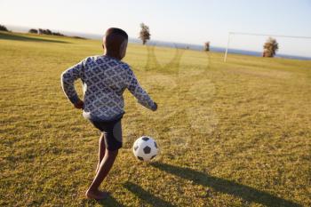 Elementary school boy playing football in an open field
