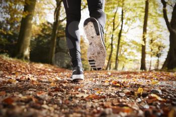 Close Up Of Male Runners Feet On Run Through Autumn Landscape