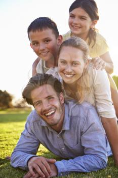 Happy white family lying in a pile on grass outdoors