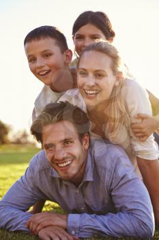 Piled up happy white family lying on grass looking away