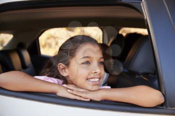 Young black girl looking out of car window smiling, front view