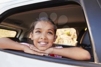 Young black girl looking up out of car window smiling