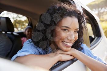 Smiling young black woman looks out of a car window