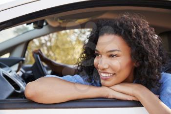 Happy young black woman looks out of a car window