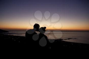 Couple kissing by the sea at sunset on a beach, silhouette