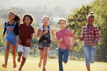 Six pre-teen friends running in a park, front view, close up