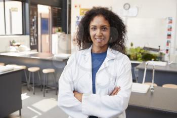 Female teacher in lab coat smiling in school science room