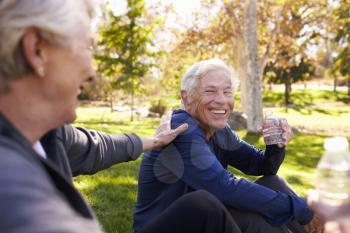 Senior Couple Resting After Exercising In Park Together
