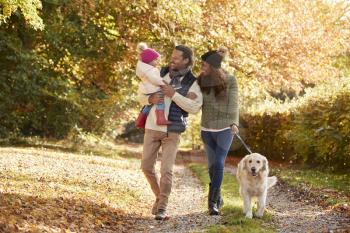 Family With Daughter And Dog Enjoy Autumn Countryside Walk