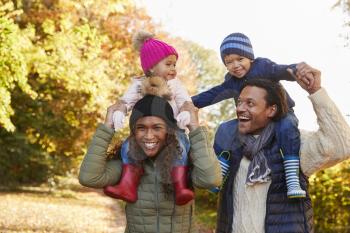 Autumn Walk With Parents Carrying Children On Shoulders