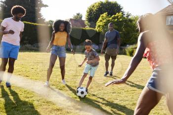 Adult family playing football with young son in garden