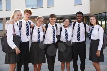 Portrait Of Smiling Male And Female High School Students Wearing Uniform Outside College Building