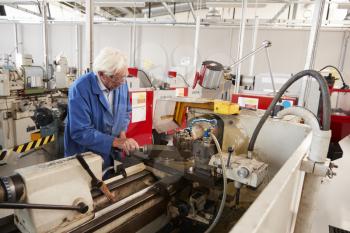 Senior engineer operating industrial machinery in a factory