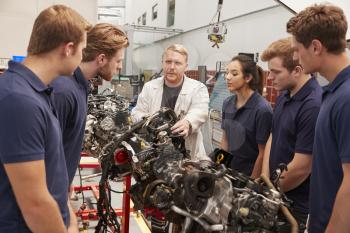 Mechanic showing parts of an engine to apprentices, close up