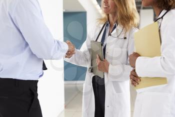 Three male and female doctors shaking hands, mid section