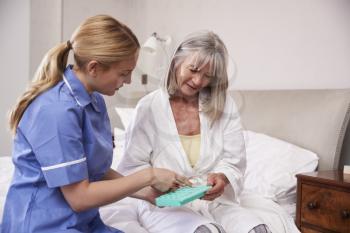 Nurse Helping Senior Woman To Organize Medication On Home Visit