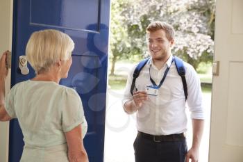 Senior woman opens door to male care worker showing his ID