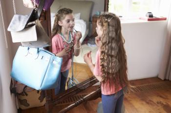 Young Girl Playing Dressing Up Game In Front Of Mirror At Home