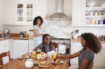 Three Teenage Girls Eating Breakfast In Kitchen Together