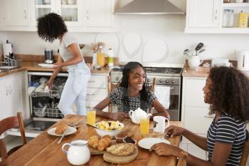 Three Teenage Girls Clearing Table After Family Breakfast