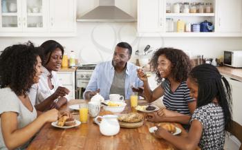 Family With Teenage Children Eating Breakfast In Kitchen