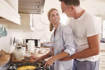Affectionate Mature Couple Prepare Breakfast In Kitchen Together