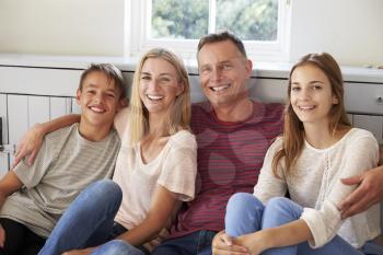 Portrait Of Smiling Family Relaxing On Seat At Home