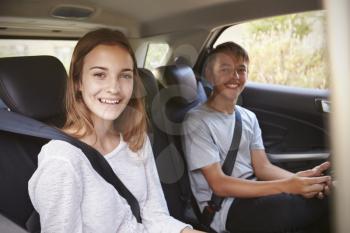 Portrait Of Teenage Children In Back Seat Of Car On Road Trip