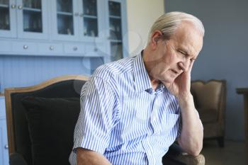 Senior Man Sitting In Chair At Home Suffering From Depression